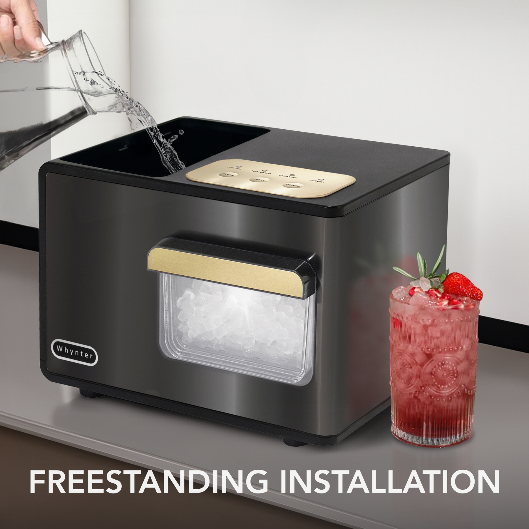 Whynter IBX-388BG  Black ice maker with gold accents on a kitchen counter, next to a red cocktail.