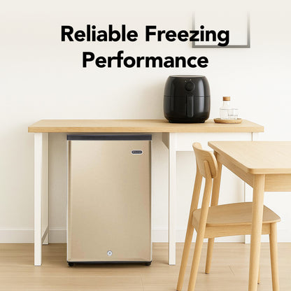 CUF‑210SSG Small refrigerator next to a dining table with chairs, featuring text about reliable freezing performance.